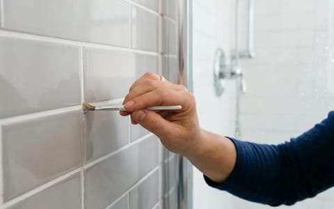 Applying clear grout sealer to shower tile lines
