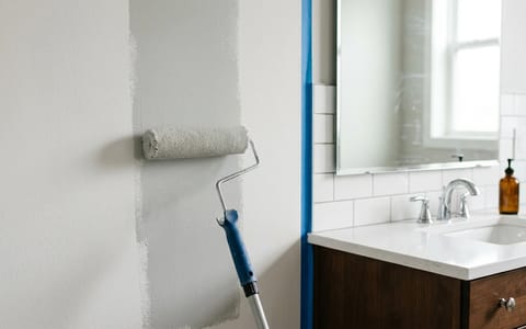 Applying fresh satin paint to a bathroom wall