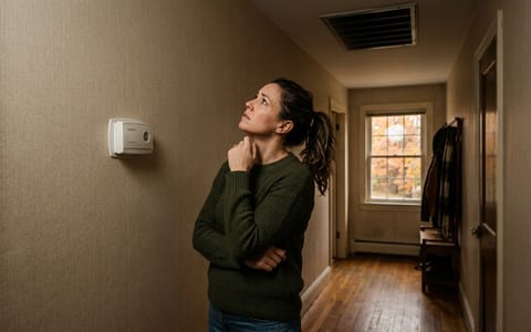 Homeowner looking concerned at a heating vent