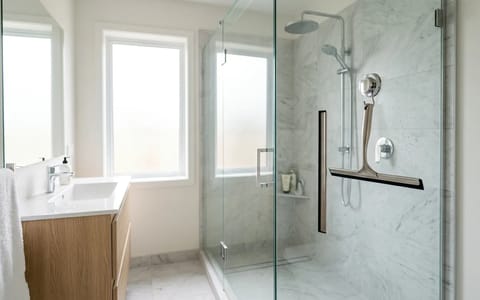 A sparkling clean frameless glass shower door in a modern bathroom with a squeegee hanging inside.