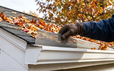 Close-up of a stainless steel micro-mesh gutter guard being installed on a residential home
